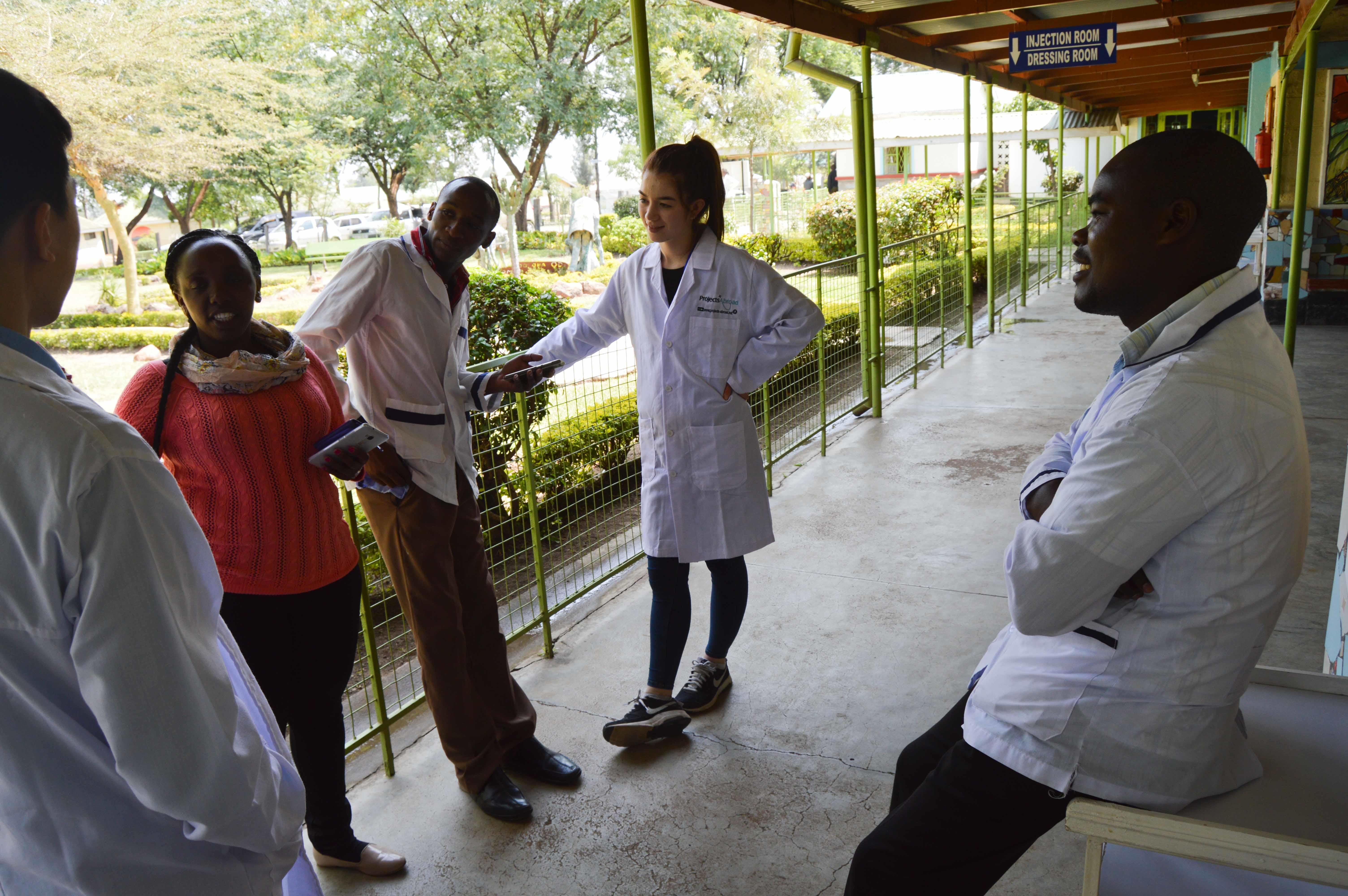 A group of interns and local doctors having a conversation outside the local hospital during their occupational therapy internship in Kenya with Projects Abroad. Projects Abroad occupational therapy in Kenya interns are pictured conversing with local doctors outside the hospital during their work experience.
